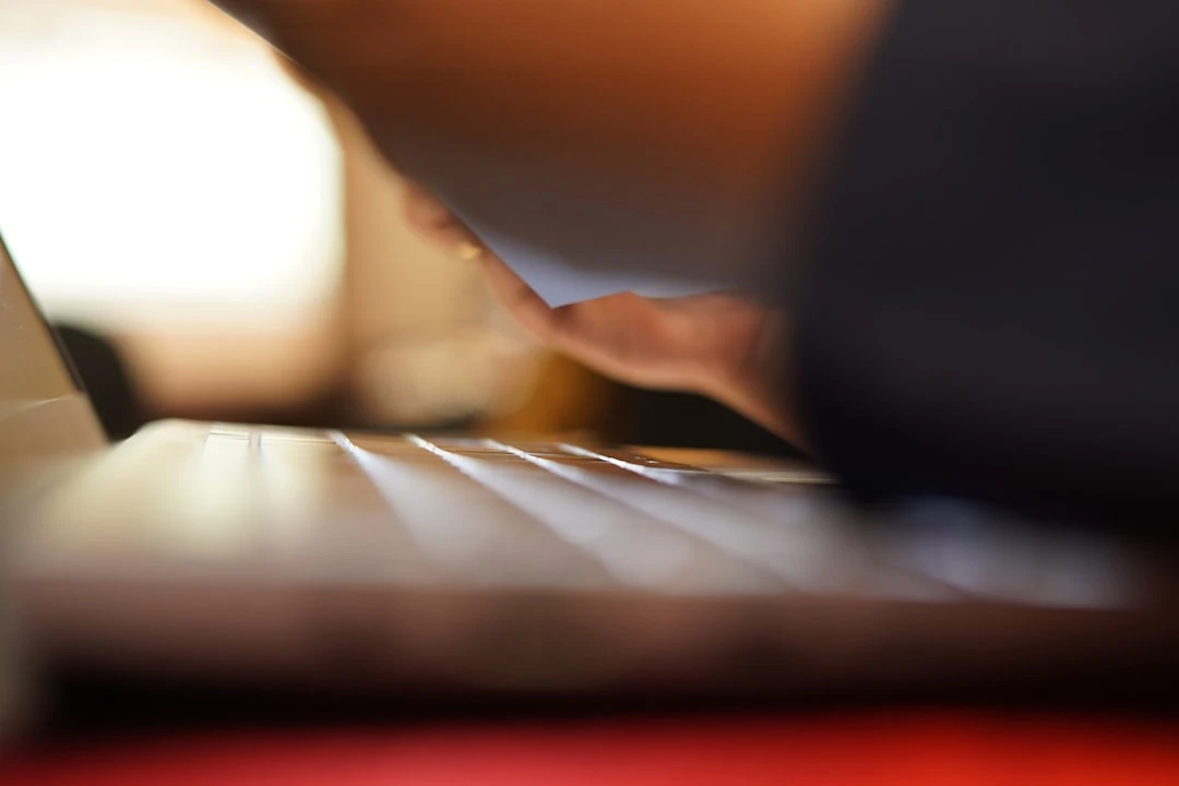 Người đang gõ trên máy tính với một cốc cà phê bên cạnh